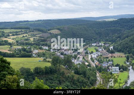 Vue élevée du château de Bourscheid sur une vallée verdoyante, un village, une rivière, une route et des collines boisées au Luxembourg. Banque D'Images
