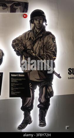 Bastogne, Belgique - 21 juil. 25 : Illustration d'un parachutiste américain éclairé par derrière avec un fusil, exposée au musée de la guerre de Bastogne à Bastogne, Belgique. Banque D'Images
