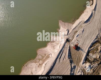 Vue aérienne des opérations de dragage et de terrassement sur un chantier de construction avec du sable excavé, la construction d'un talus et un bassin d'eau. Banque D'Images