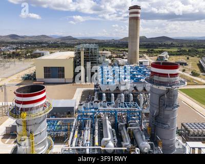 Vue aérienne d'une centrale thermoélectrique comportant des tours de refroidissement, des cheminées industrielles et des systèmes de tuyauterie complexes sous un ciel dégagé à San Luis Po Banque D'Images