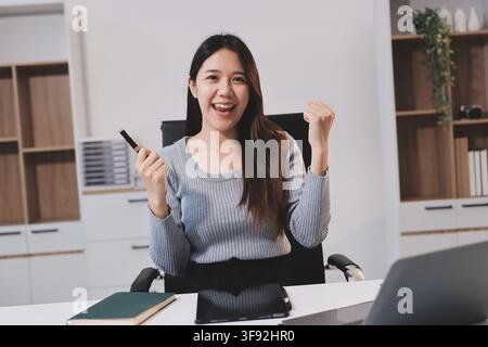 jeune femme travaille sur un ordinateur portable dans un environnement de bureau moderne, mettant en valeur une atmosphère concentrée et productive. Elle est vêtue d'une chemise blanche professionnelle Banque D'Images