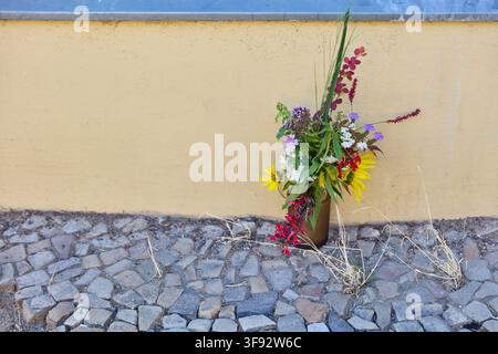 Bouquet rustique de fleurs sauvages et de graminées devant un mur de maison jaune Banque D'Images