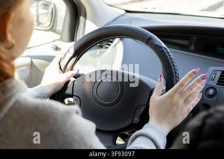 Close up d'une conductrice tenant le volant lors d'une conduite matinale lumineuse, symbolisant la mobilité personnelle, la liberté de voyage et la sécurité routière en Banque D'Images