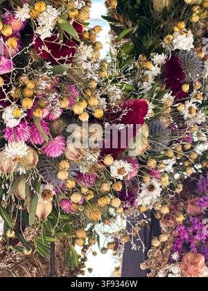 Close-up détaillé d'une couronne de fleurs séchées artisanale mettant en avant des fleurs conservées, des capsules de graines et du feuillage décoratif Banque D'Images