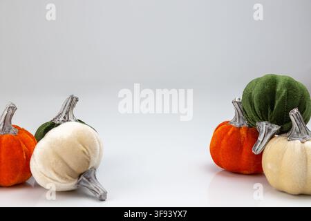 Une composition horizontale mettant en scène un groupe de quatre citrouilles décoratives de couleurs variées : deux orange, une blanc ivoire et une vert foncé. L'arrang Banque D'Images
