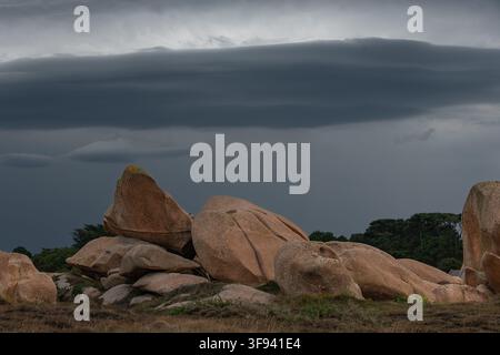 Roches de granit rose sur la Côte de Granit Rose en Bretagne, France, sous un ciel nuageux dramatique. Banque D'Images