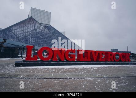 La neige recouvre la place alors que « Long Live Rock » se tient devant la pyramide de verre du Temple de la renommée du rock à Cleveland Banque D'Images
