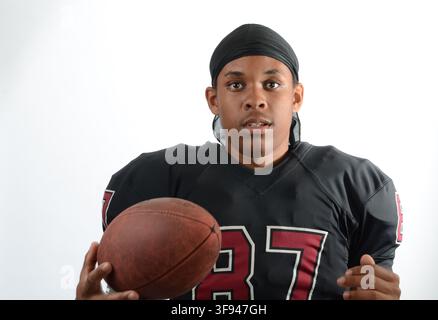 Jeune joueur de football américain afro-américain dans un maillot noir uni numéroté 87, photographié devant un fond blanc de studio. Banque D'Images