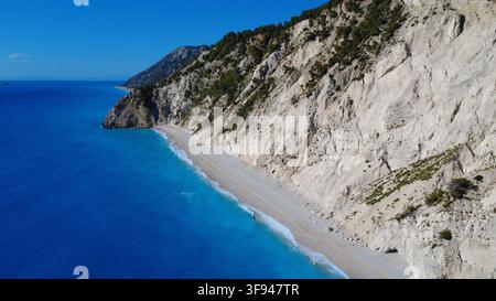 Vue aérienne d'une plage turquoise isolée nichée sous des falaises de calcaire blanc dramatiques sur une côte méditerranéenne. Banque D'Images