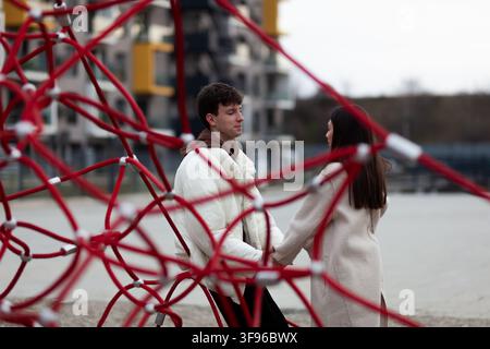 Un couple en conversation en plein air au milieu d'un environnement urbain avec un filet rouge unique au premier plan Banque D'Images