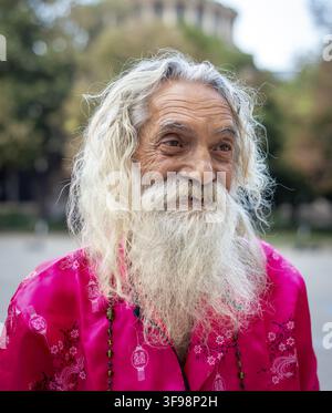 Homme senior portrait d'homme flamboyant barbu avec long Cheveux blancs portant des vêtements roses dans les rues de Sofia Bulgarie Banque D'Images