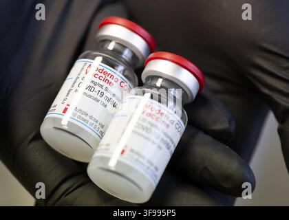 Flacons à doses multiples du vaccin Moderna Covid-19 mARN pour usage intramusculaire dans les mains d'un médecin portant des gants noirs. Concept de soins de santé liés à l'immunisation Banque D'Images