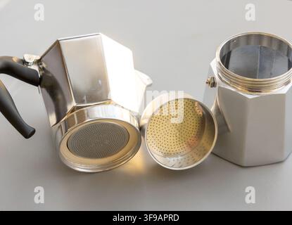 Une moka brillante et démontée repose sur une surface grise simple Banque D'Images