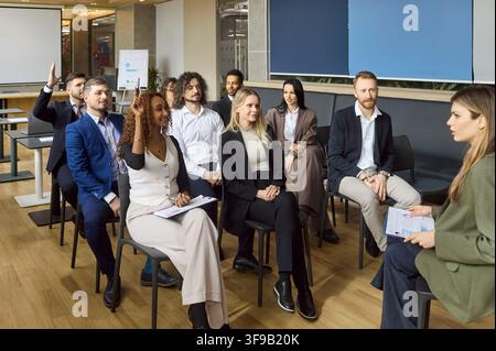 Équipe d'affaires diversifiée dans un atelier de bureau levant les mains pendant une formation d'entreprise Banque D'Images