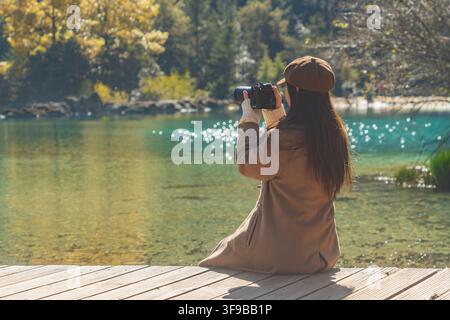 Femme agenouillée pour photographier le lac turquoise, Blue Moon Valley, Lijiang, Chine Banque D'Images