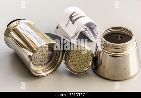 Les composants démontés de la moka et le manuel d'instructions sont posés sur une surface blanche Banque D'Images