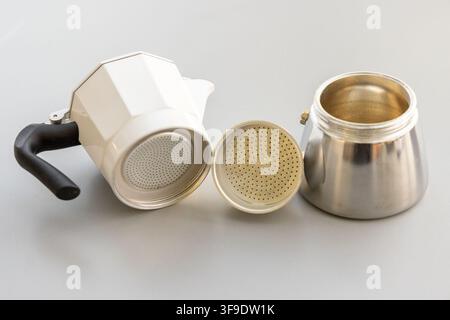 Les pièces d'une cafetière moka blanche sont démontées sur un fond gris clair Banque D'Images