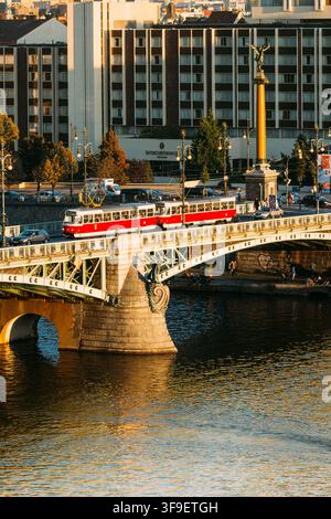 Tramway rouge traversant le pont Čechův au-dessus de la Vltava à Prague Banque D'Images