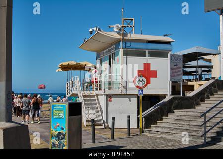 Maspalomas, Espagne – 15 août 2026 : Panneau de la station d'urgence en bord de plage et du centre commercial le long d'une allée piétonne, des escaliers et l'océan au loin Banque D'Images