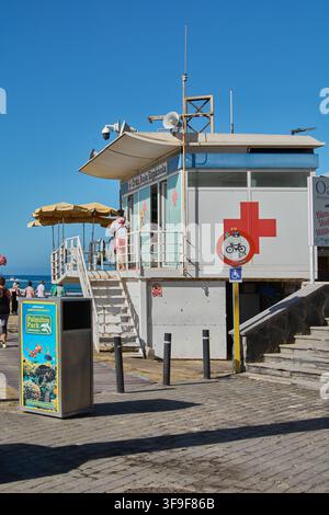 Maspalomas, Espagne – 15 août 2026 : Station de sauvetage côtier avec panneau rouge à croix visible, escalier extérieur, panneaux d'information, a Banque D'Images
