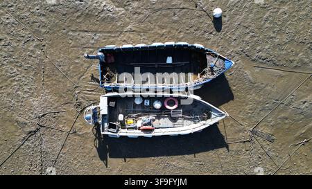 Vue aérienne de deux petits bateaux de pêche reposant sur les vasières à marée basse à Billiers, en Bretagne, France. Banque D'Images