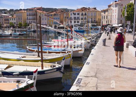 Un touriste marchant le long du quai du port riverain bordé de bateaux traditionnels à La Ciotat, Côte d'Azur, France. Banque D'Images