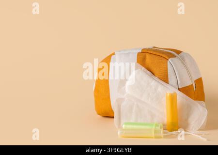Sac à cosmétiques, serviettes hygiéniques et tampons sur fond jaune Banque D'Images