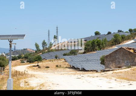 Des rangées de panneaux photovoltaïques recouvrent un vaste paysage aride, capturant la lumière du soleil pour la production d'énergie renouvelable à côté des tours de transmission Banque D'Images