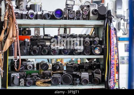 Bichkek, Kirghizistan - 07 juillet 2022 : Appareils photo vintage exposés sur une étagère en bois dans une boutique de photographie, divers modèles et objectifs visibles Banque D'Images