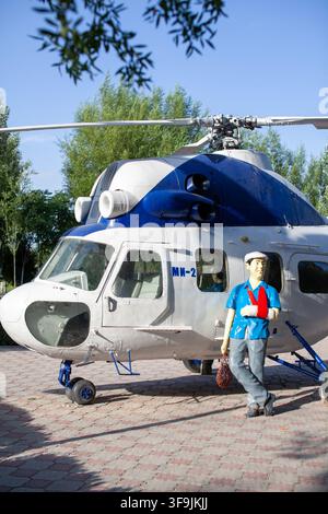 Kant, Kirghizistan - 08 juillet 2022 : Modèle d'hélicoptère au design bleu et blanc garé à l'extérieur, un pilote mannequin en chemise bleue se tient à côté Banque D'Images