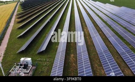Ferme solaire générant de l'énergie propre avec de longues rangées de panneaux photovoltaïques dans un champ vert, vue aérienne Banque D'Images
