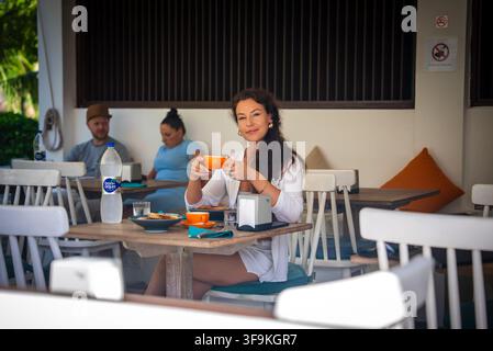 Femme buvant du café à une table de restaurant en plein air aux Maldives Banque D'Images