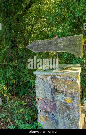 Ancien panneau fléché en bois usé sur un pilier de pierre dans un cadre rural verdoyant à Coesfeld, Allemagne Banque D'Images
