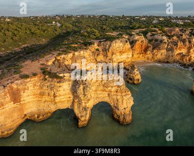 Vue drone de la plage de Praia da Marinha en Algarve, Portugal, avec falaises dorées, arches marines, eaux turquoise de l'Atlantique, et des formations rocheuses côtières. Banque D'Images