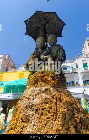 Close-up de la fontaine historique des Amoureux (Fontana degli Innamorati) à Amalfi, en Italie. La sculpture en pierre couverte de mousse représente un jeune couple embr Banque D'Images