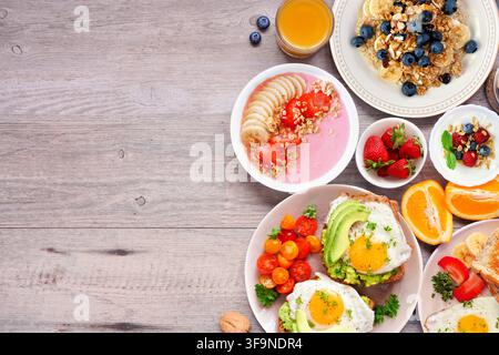 Accompagnement sain pour le petit-déjeuner ou le brunch sur un fond en bois. Vue de dessus. Toast à l’avocat, bols de smoothie, avoine, yaourt et une collection d’aliments nutritifs Banque D'Images