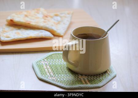 Petit-déjeuner matinal confortable avec du thé chaud et du pain plat fraîchement cuit sur une table en bois rustique Banque D'Images