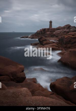 Vue du phare de Men Ruz sur la côte de granit rose avec des vagues qui s'écrasent et un ciel nuageux à Perros-Guirec, en Bretagne, France. Banque D'Images