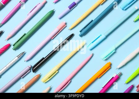 Assortiment coloré de stylos à encre gel et de stylos à bille disposés en diagonale sur un fond bleu clair, papeterie et fournitures de bureau Banque D'Images