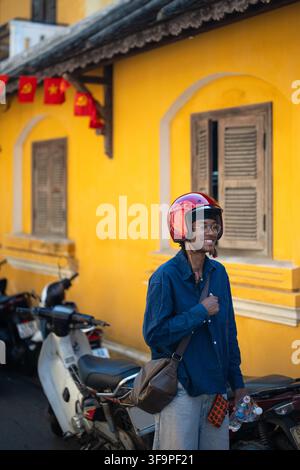Homme noir souriant et joyeux portant un casque de moto rouge posant à côté d'un café vintage au Vietnam. Banque D'Images