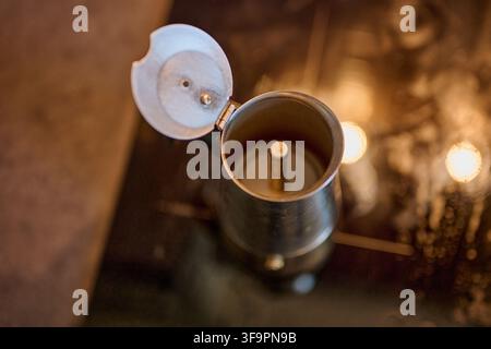 Vue par le dessus d'une cafetière à moka argentée vide ouverte reposant sur une cuisinière. Banque D'Images