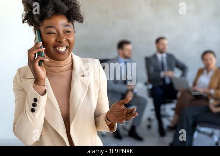 Une femme d'affaires confiante mène sa vie de bureau occupée, multitâche avec la communication smartphone Banque D'Images