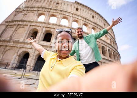 Heureux couple en vacances ensemble, prenant un selfie joyeux avec le colisée à Rome. Banque D'Images