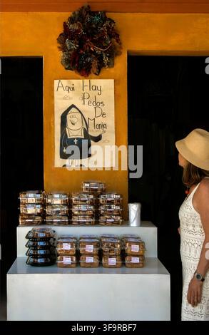 Femme regardant une enseigne faisant la promotion de Pedos de Monja, ou « Pétons de Nonne », une confiserie au chocolat populaire, à l'extérieur d'une boulangerie à San Miguel de Allende, au Mexique Banque D'Images