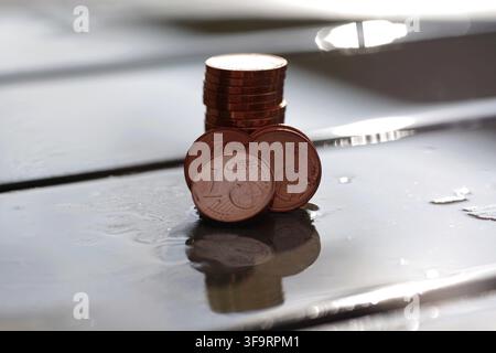 Piece de 1 euro cent, macro, petite monnaie, réflexion, réflexions de lumière, plusieurs pièces de cent centimes empilées se reflètent sur une surface humide Banque D'Images