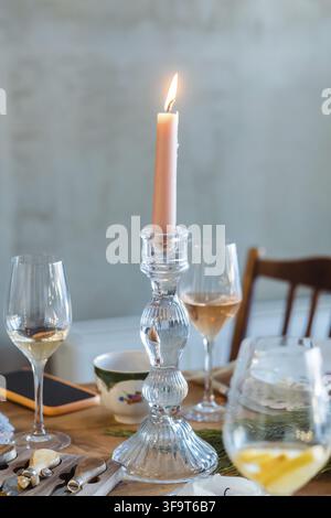 Bougie rose dans un candélabre sur une table, gros plan avec des verres de vin et de champagne Banque D'Images