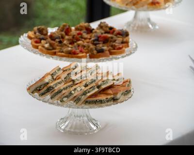 Une sélection magnifiquement arrangée de finger foods et canapés savoureux servis sur des plateaux en cristal, parfaits pour les événements et les fêtes Banque D'Images