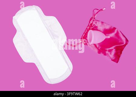Coupe menstruelle et protection hygiénique classique sur fond rose, vue de dessus, espace de copie. Concept zéro déchet. Produits menstruels écologiques Banque D'Images