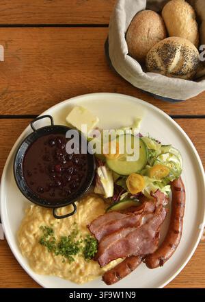 Petit-déjeuner traditionnel typiquement polonais composé de bacon, saucisses, œufs brouillés, salade fraîche, confiture et beurre servi avec du pain dans un restaurant, Pol Banque D'Images