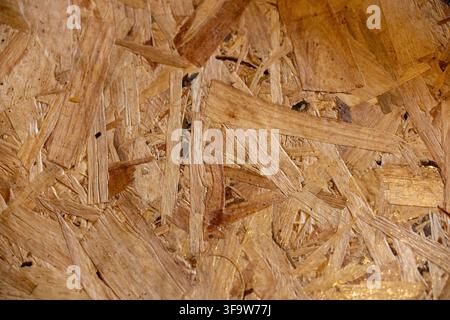 Une texture de panneau de fibres de bois avec un motif de copeaux naturels superposés, une surface rugueuse, un ton brun chaud et des détails de matériaux de construction rustiques Banque D'Images